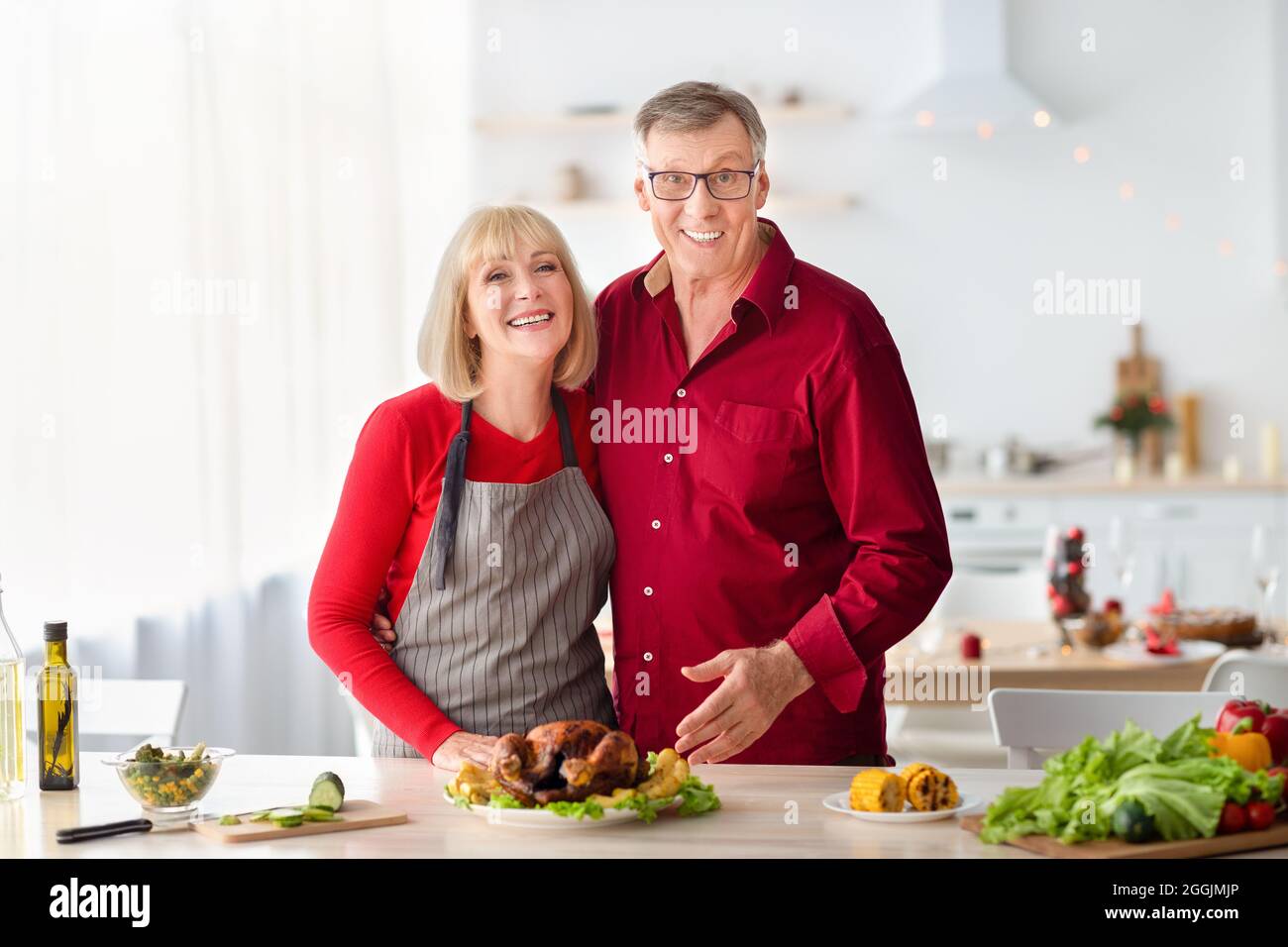 Joyeux couple senior posant, cuisant la dinde pour Noël ou le dîner de Thanksgiving, préparant le repas de vacances dans la cuisine Banque D'Images