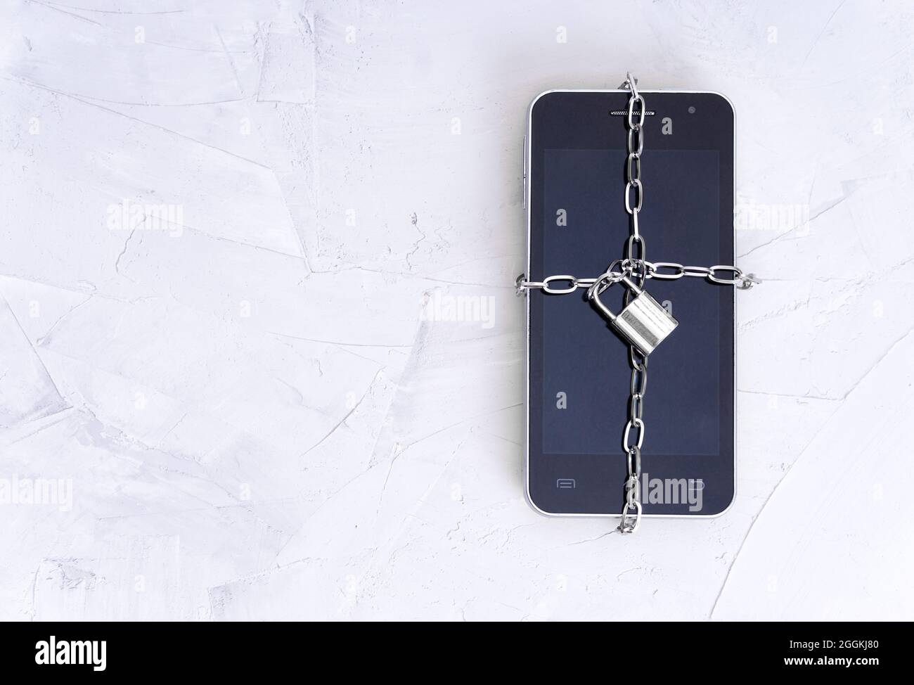 Vue de dessus d'un smartphone enveloppé d'un verrou de chaîne sur une table en béton. Concept de sécurité mobile. Banque D'Images