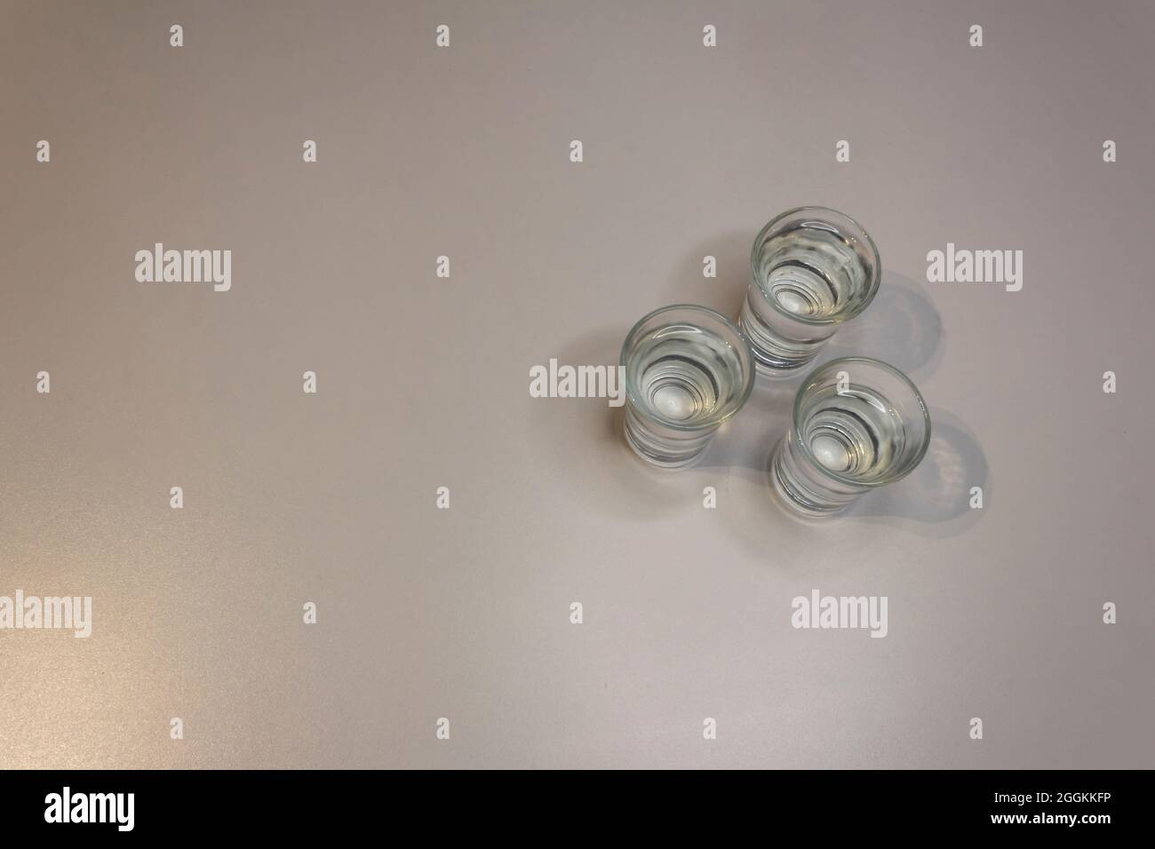 Trois coups de tequila, petits coups de tequila sur fond blanc. Tableau blanc en arrière-plan. Banque D'Images