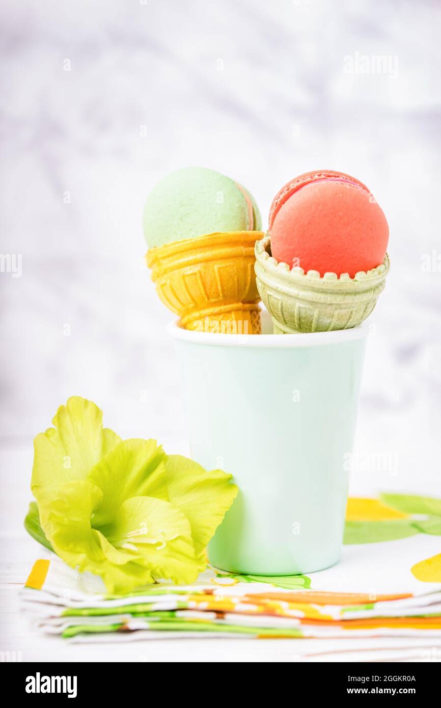 Tasse de cachets pour glace avec macarons et gladiolus vert sur fond de marbre clair Banque D'Images