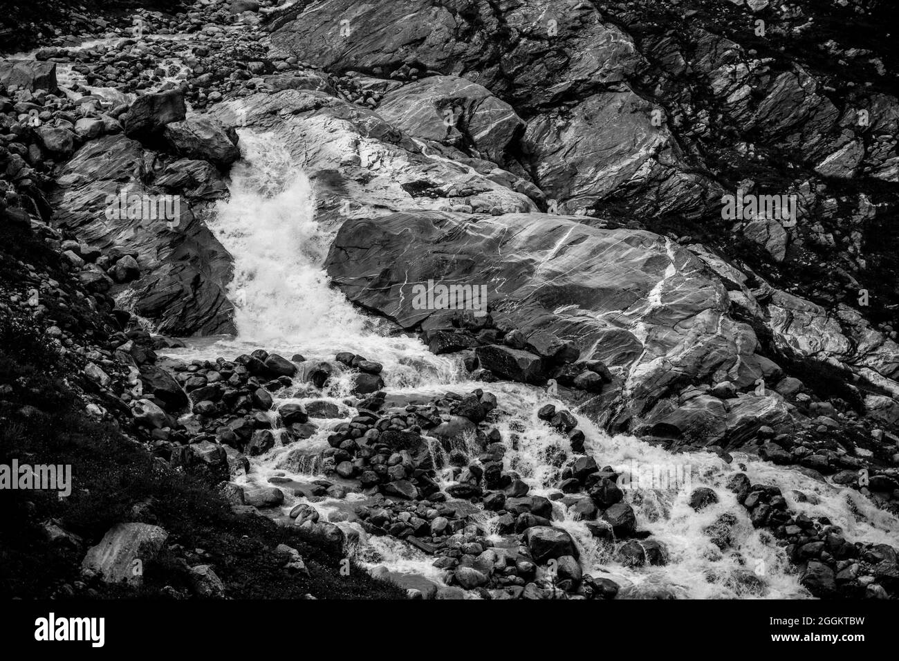 Cascade alpine sauvage sur le ruisseau de montagne de Schlatenbach. Vallée de Gschloesstal, parc national Hohe Tauern, Tyrol oriental, Alpes autrichiennes. Image en noir et blanc. Banque D'Images