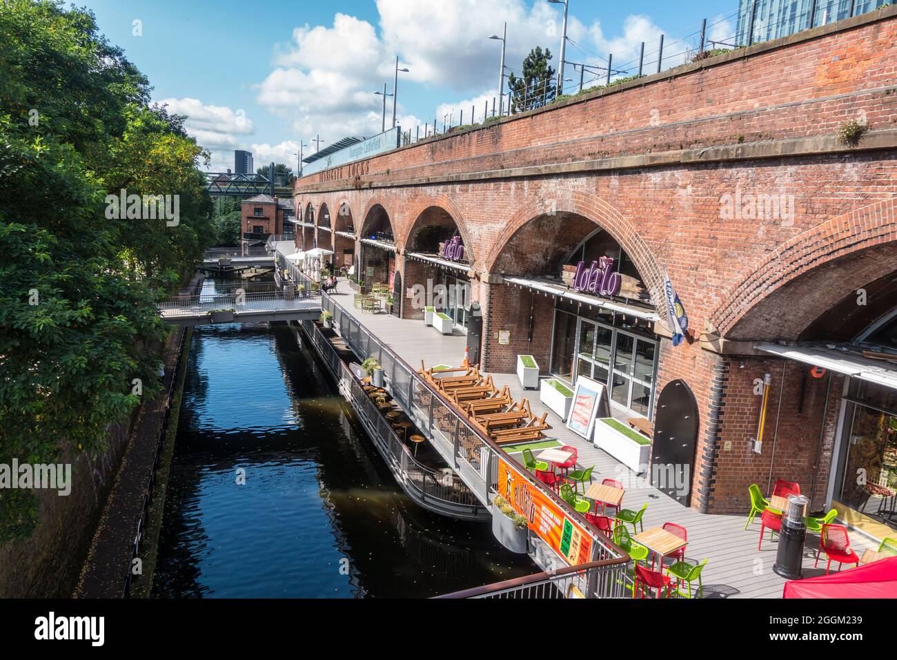 Vue d'ensemble des restaurants et des bars sous les lignes de chemin de fer et de tramway qui s'exécutent à côté du canal à Deansgate, Manchester Banque D'Images