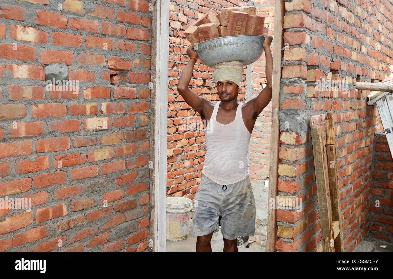 Main-d'œuvre transportant de la brique sur la tête du chantier Banque D'Images