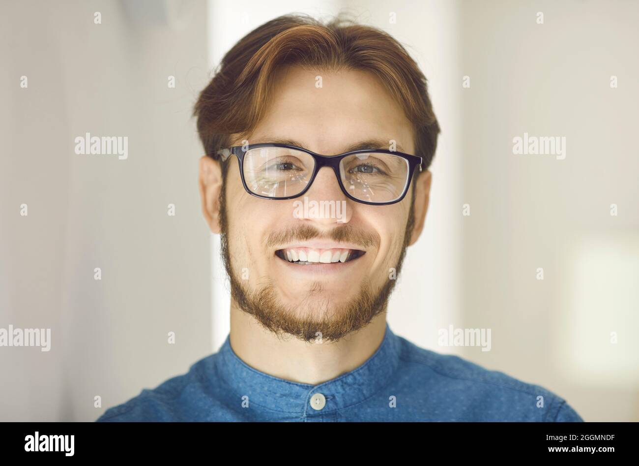 Portrait d'un jeune travailleur de bureau ou d'un homme d'affaires heureux en lunettes souriant à l'appareil photo Banque D'Images