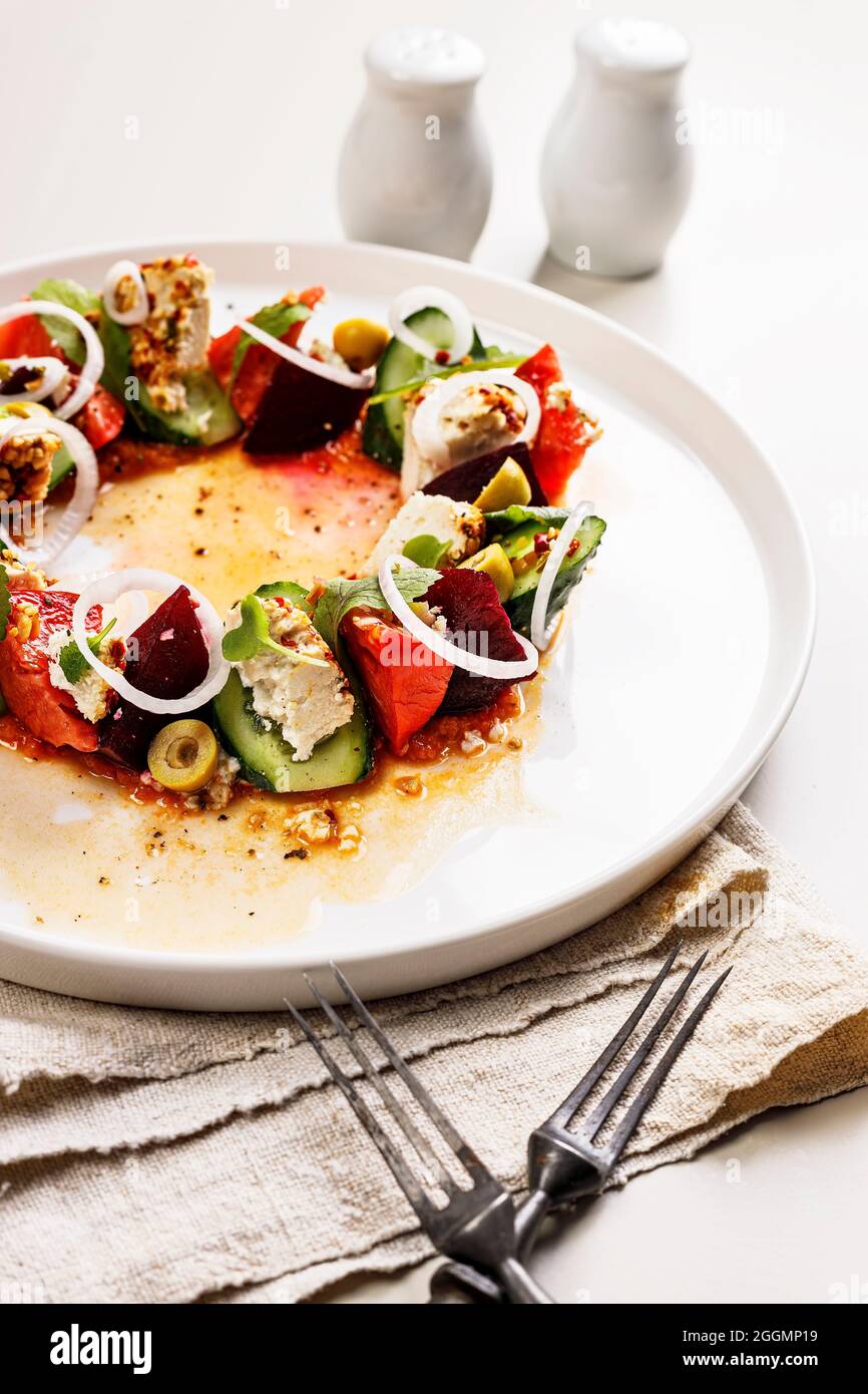 Salade de légumes frais et appétissante en gros plan avec betteraves, fromage de chèvre, tomate mûre, concombre, feuilles de moutarde et sauce épicée. Délicieux et sain Banque D'Images