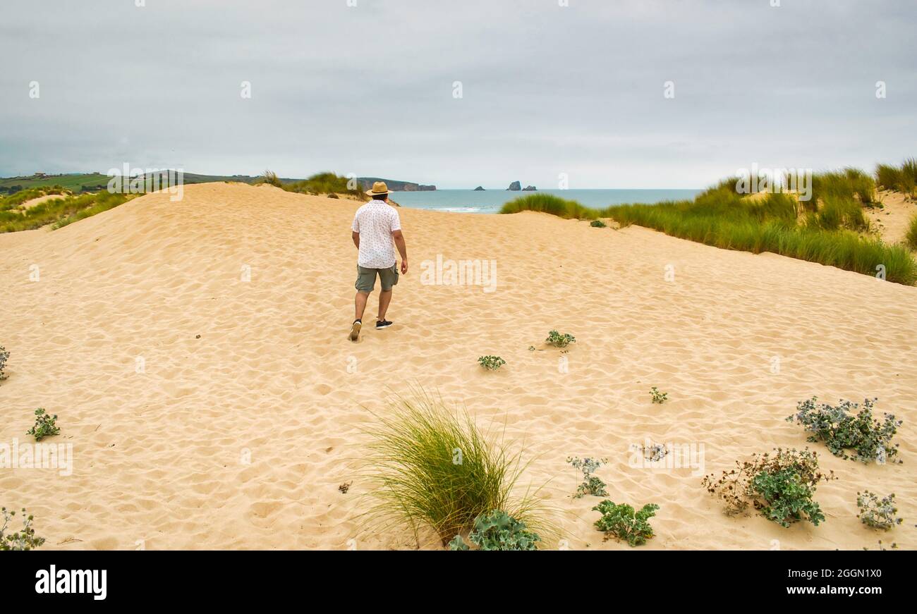 Vue sur la plage de Covachos et un homme qui marche jusqu'à la plage, Broken Coast, Cantabrie, Espagne Banque D'Images