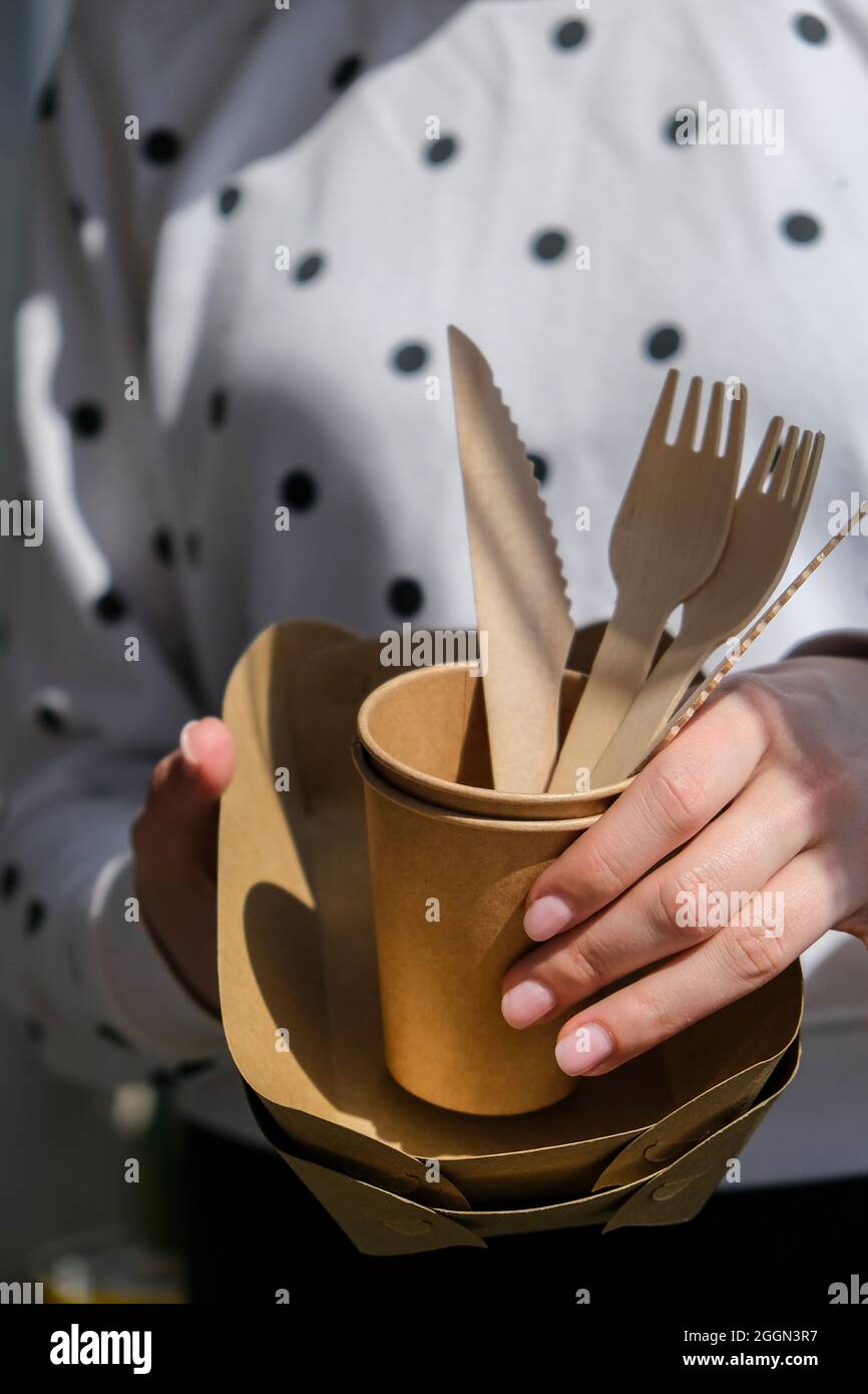 Les femmes tiennent des fourchettes en bois et des gobelets en papier avec  des assiettes. Vaisselle jetable écologique. Utilisé dans la restauration  rapide, les restaurants, les plats à emporter, les pique-niques Photo