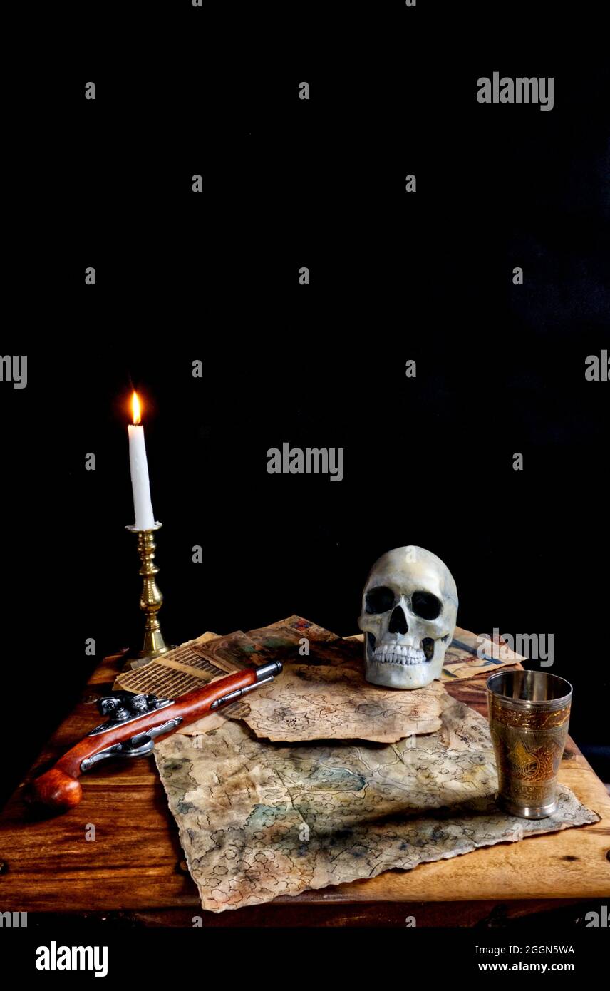 pirates table, avec pistolet à serrure, cartes et pages de vieux livres, bougie et goblet. Banque D'Images
