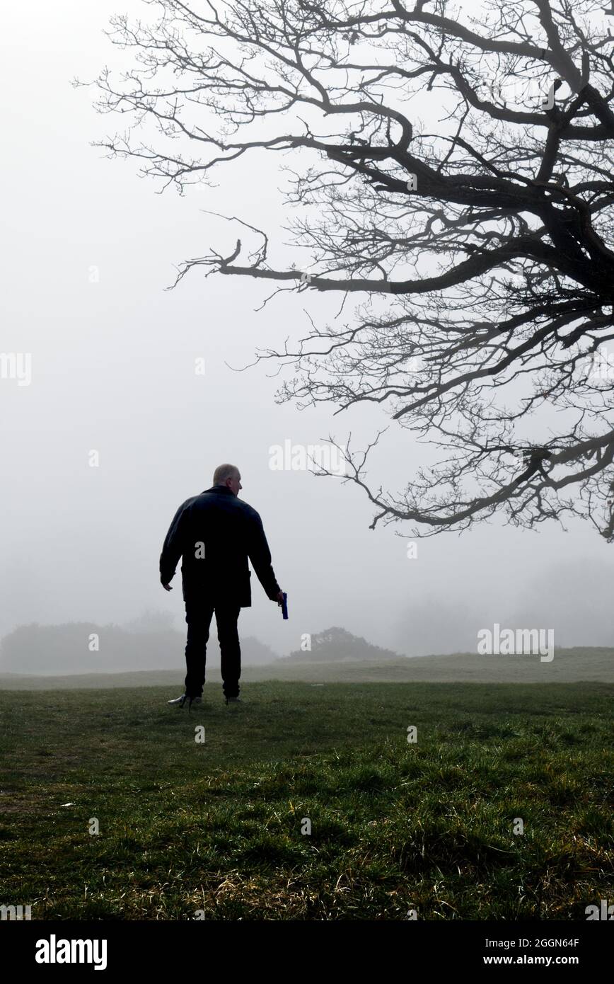 un tireur solitaire sur une lande brumeuse près d'un arbre Banque D'Images