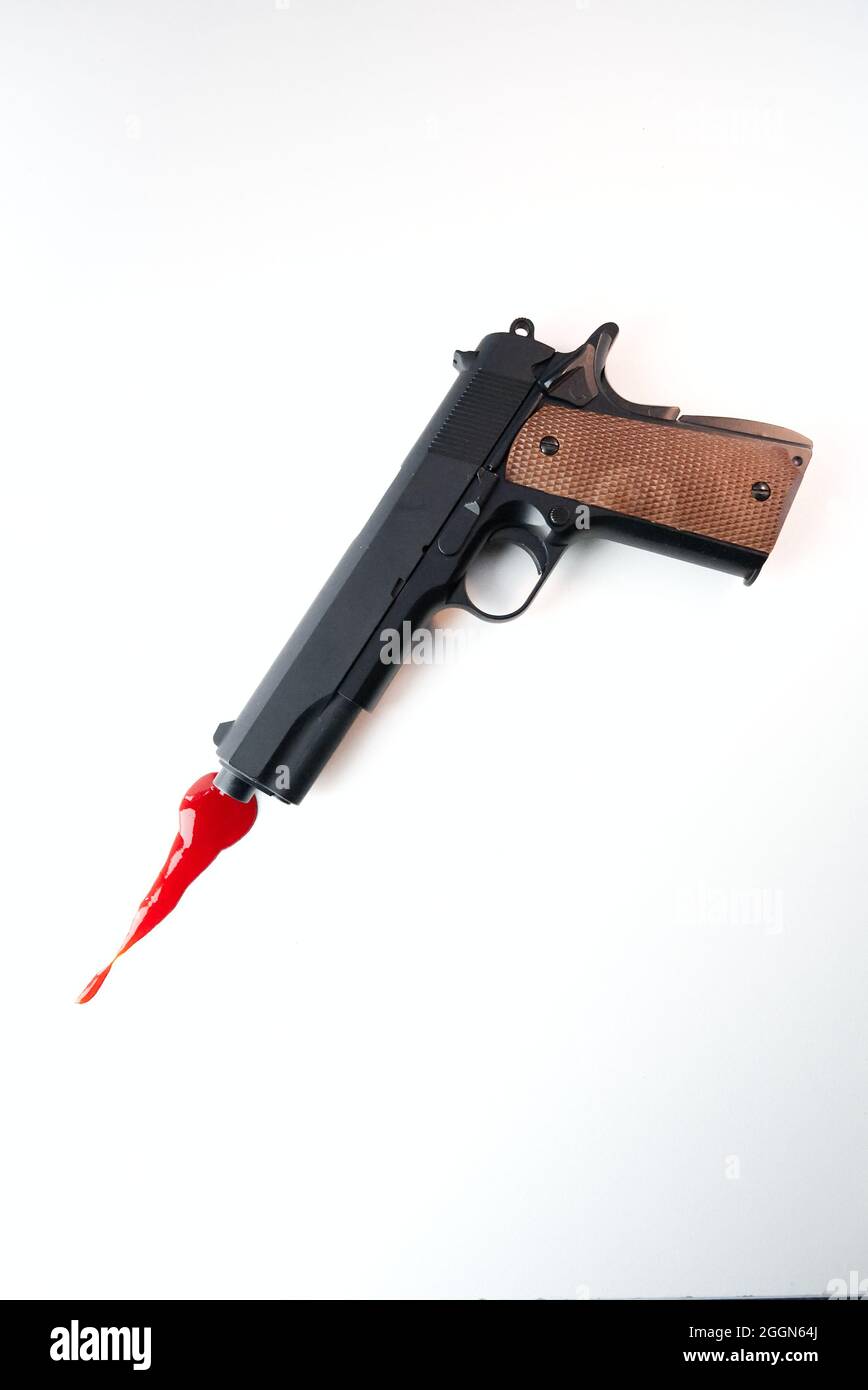 pistolet noir de reproduction moderne avec du sang par l'avant du canon ressemblant à un flash museau, sur fond blanc. (style de couverture de livre) Banque D'Images