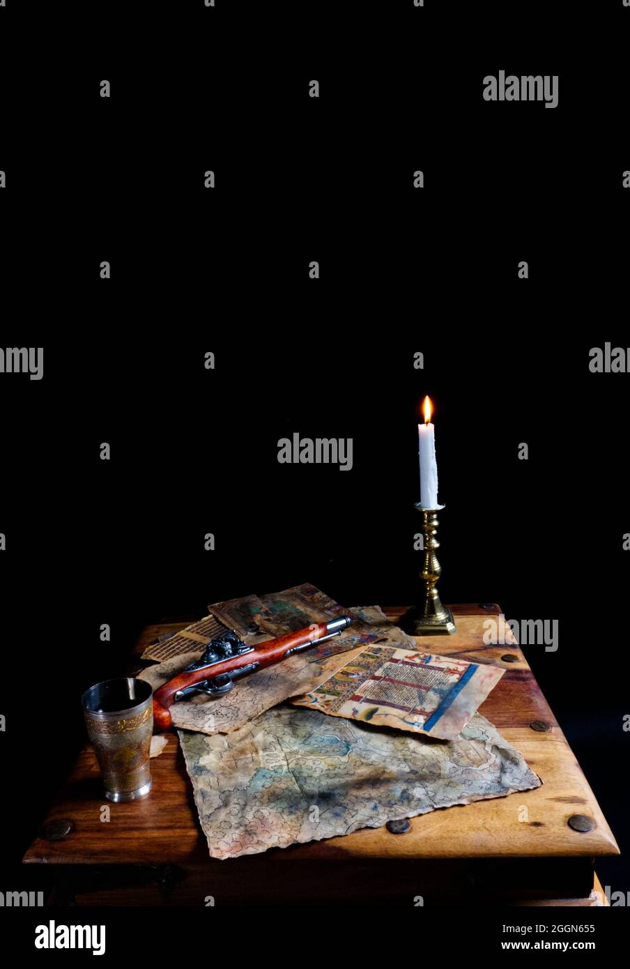 pirates table, avec pistolet à serrure, cartes et pages de vieux livres, bougie et goblet. Banque D'Images