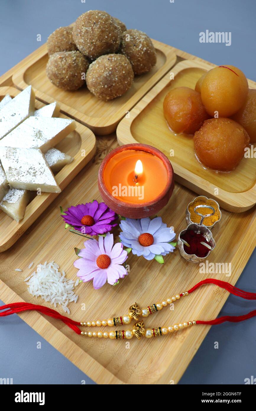 Festival indien Raksha bandhan. Rakhi thali avec diya, fleurs et tilak avec des sucreries assorties telles que Gulab Jamun, Kaju katli, et Churma Laddo. Banque D'Images Festival indien Raksha bandhan. Rakhi thali avec diya, fleurs et tilak avec des sucreries assorties telles que Gulab Jamun, Kaju katli, et Churma Laddo. Banque D'Images