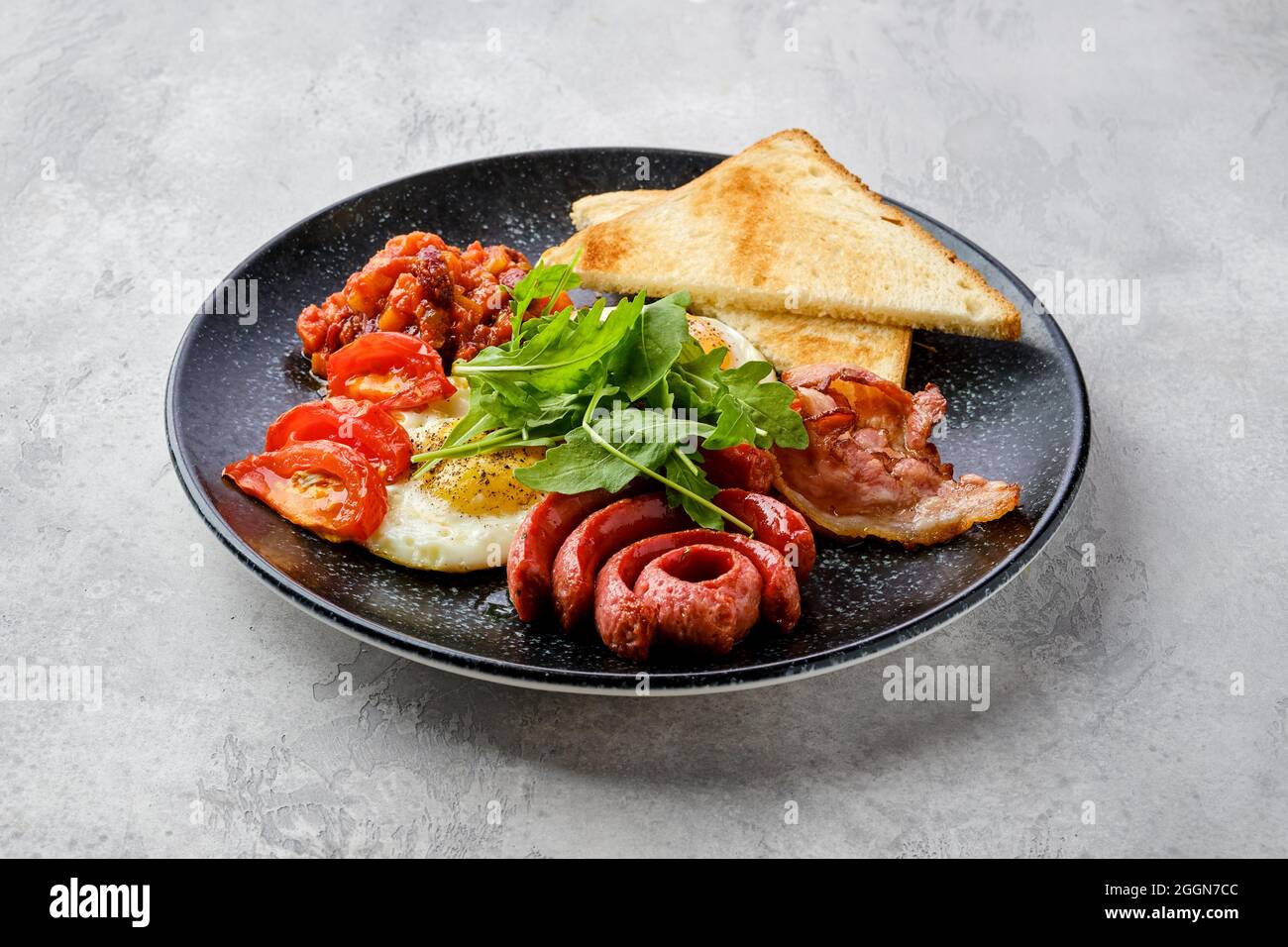 Œufs frits avec saucisse, bacon, tomates et haricots sur une assiette avec toasts Banque D'Images