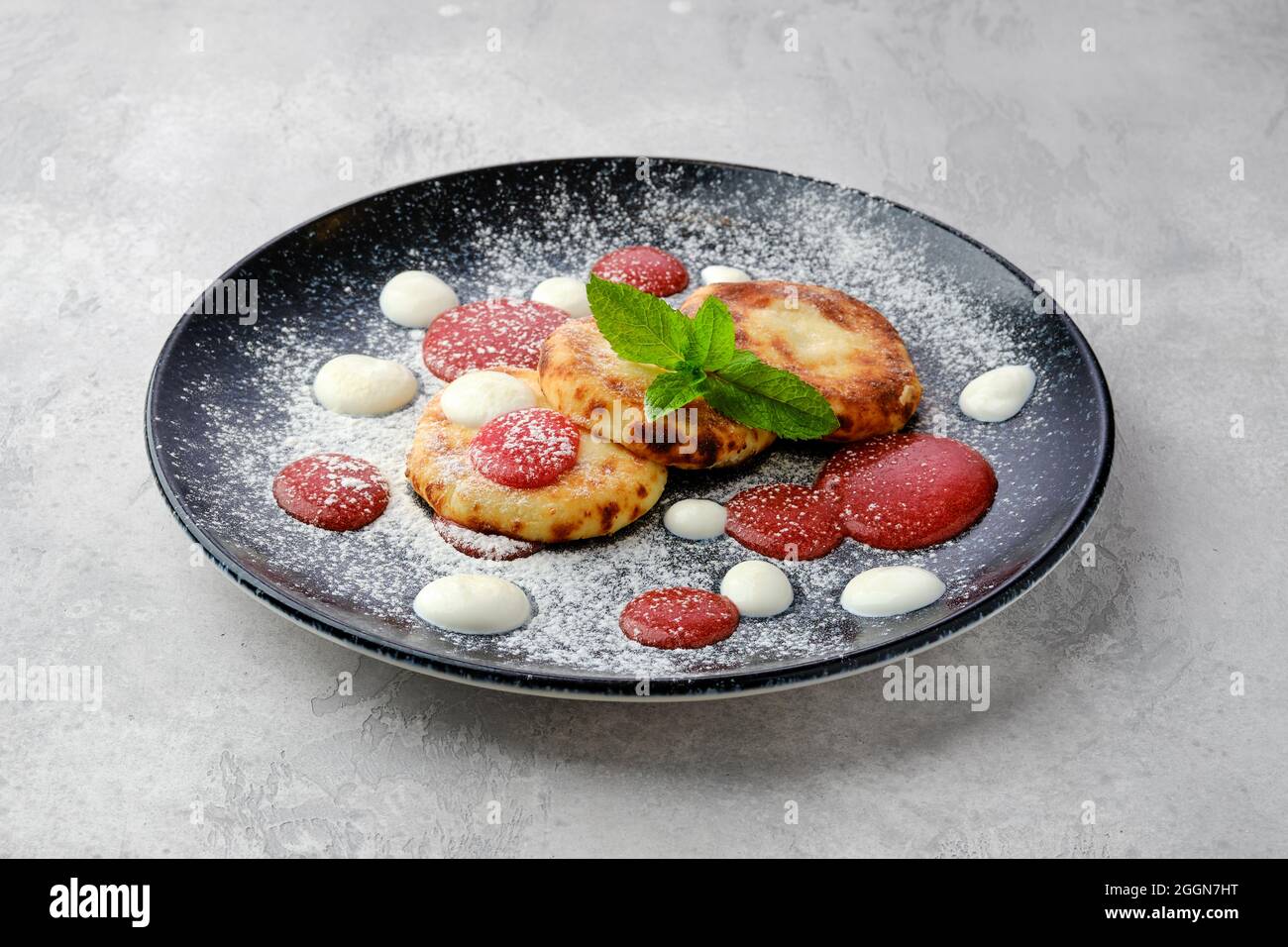 Patties de caillé sucrées avec de la crème aigre et de la confiture de fraise sur une assiette Banque D'Images