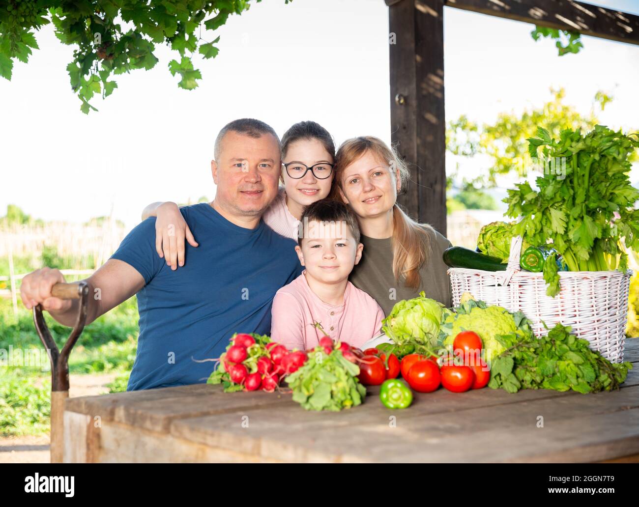 Les parents avec leurs enfants se détendent à table rustique après avoir récolté des légumes Banque D'Images