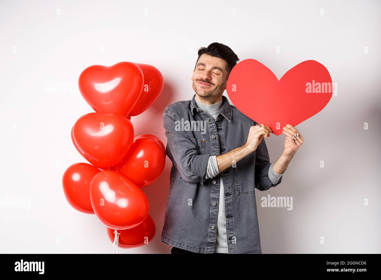 Romantique gars célébrant la Saint Valentin, enembrassant la grande carte  de coeur rouge de l'amant et souriant heureux, étant dans l'amour, debout  sur fond blanc près de rouge Photo Stock - Alamy