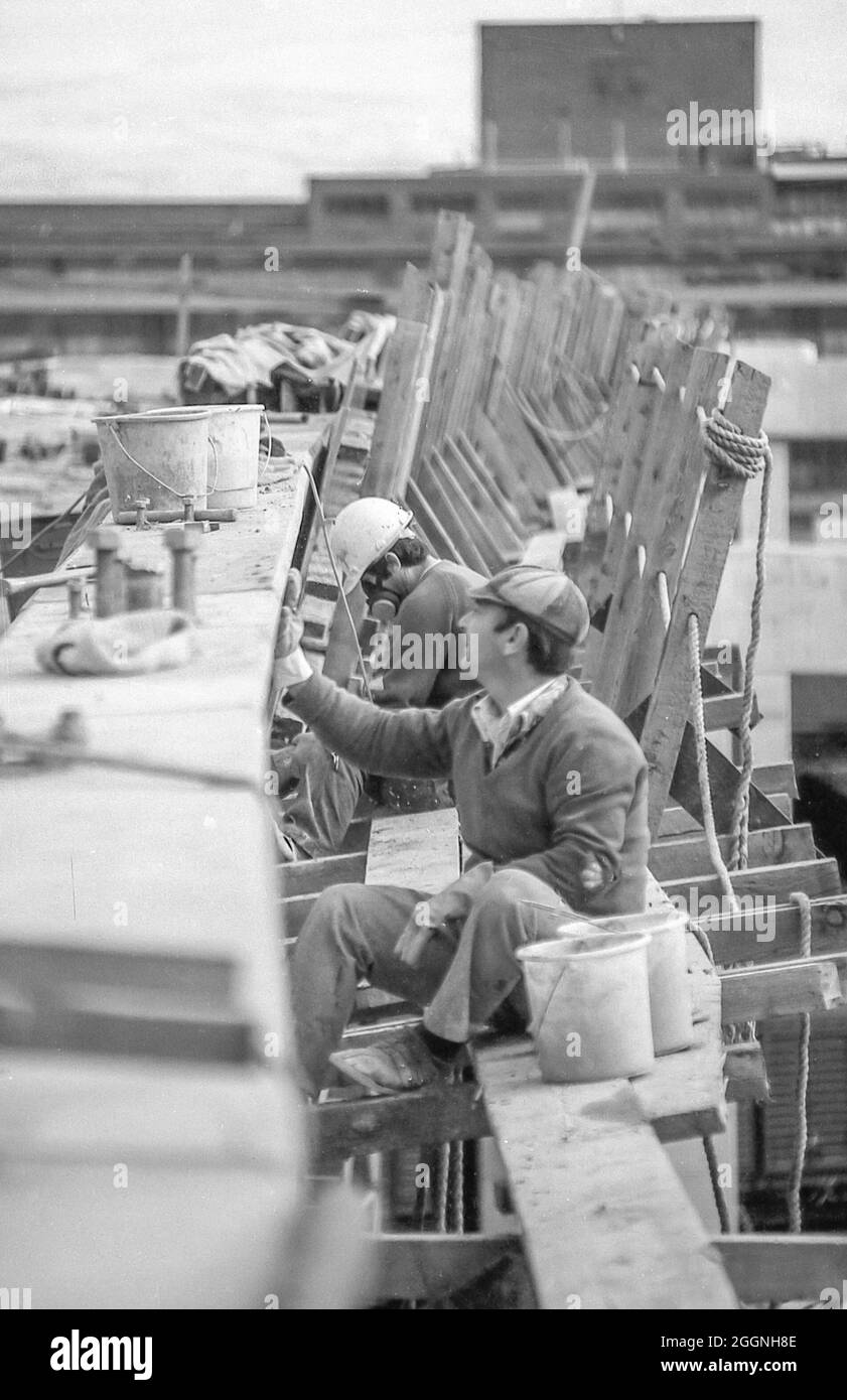 Une image des années 1970 représentant des ouvriers du bâtiment qui construisent la route du distributeur occidental en dehors de la ville et au-dessus de Darling Harbour alors qu'il était encore un chantier ferroviaire à Sydney, en Australie. Dans les années 70, il y avait peu d'équipements de sécurité et pas de vêtements haute visibilité pour les travailleurs. Banque D'Images