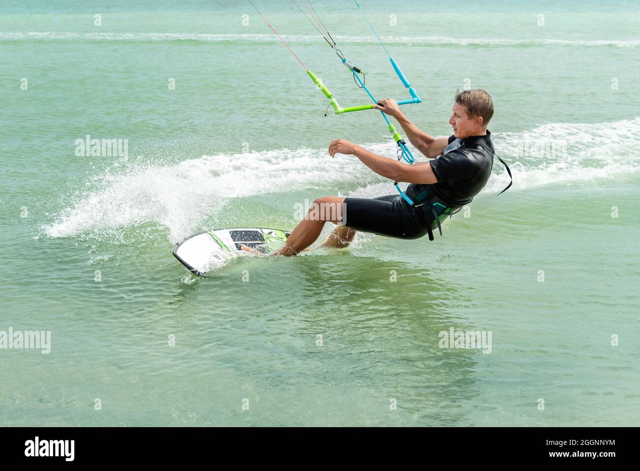 Jeune adulte de type caucasien homme personne appréciez l'équitation kite surf planche dans soleil protection uv costume le jour lumineux ensoleillé contre le ciel bleu à la mer ou l'océan Banque D'Images