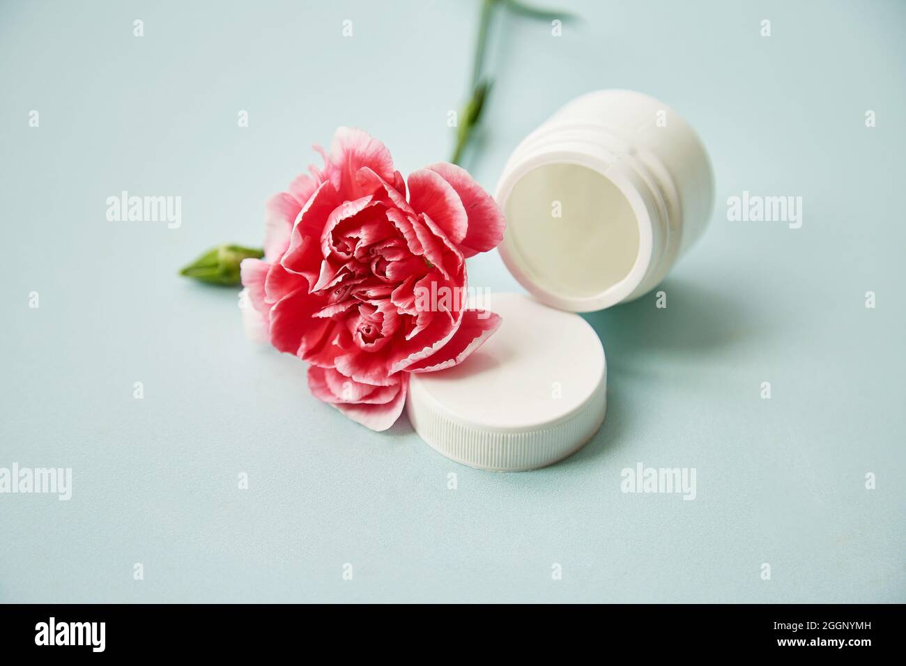 Flacons cosmétiques minimalistes avec fleur décorative rose. Produits de beauté sur fond bleu. Beauté tendance cosmétique. Photo de haute qualité Banque D'Images
