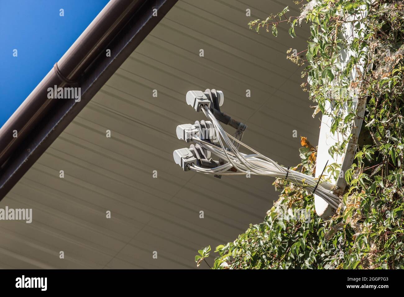 Récepteur de télévision par satellite récepteur de signal et antenne TV près du toit de la maison contre le ciel. Banque D'Images