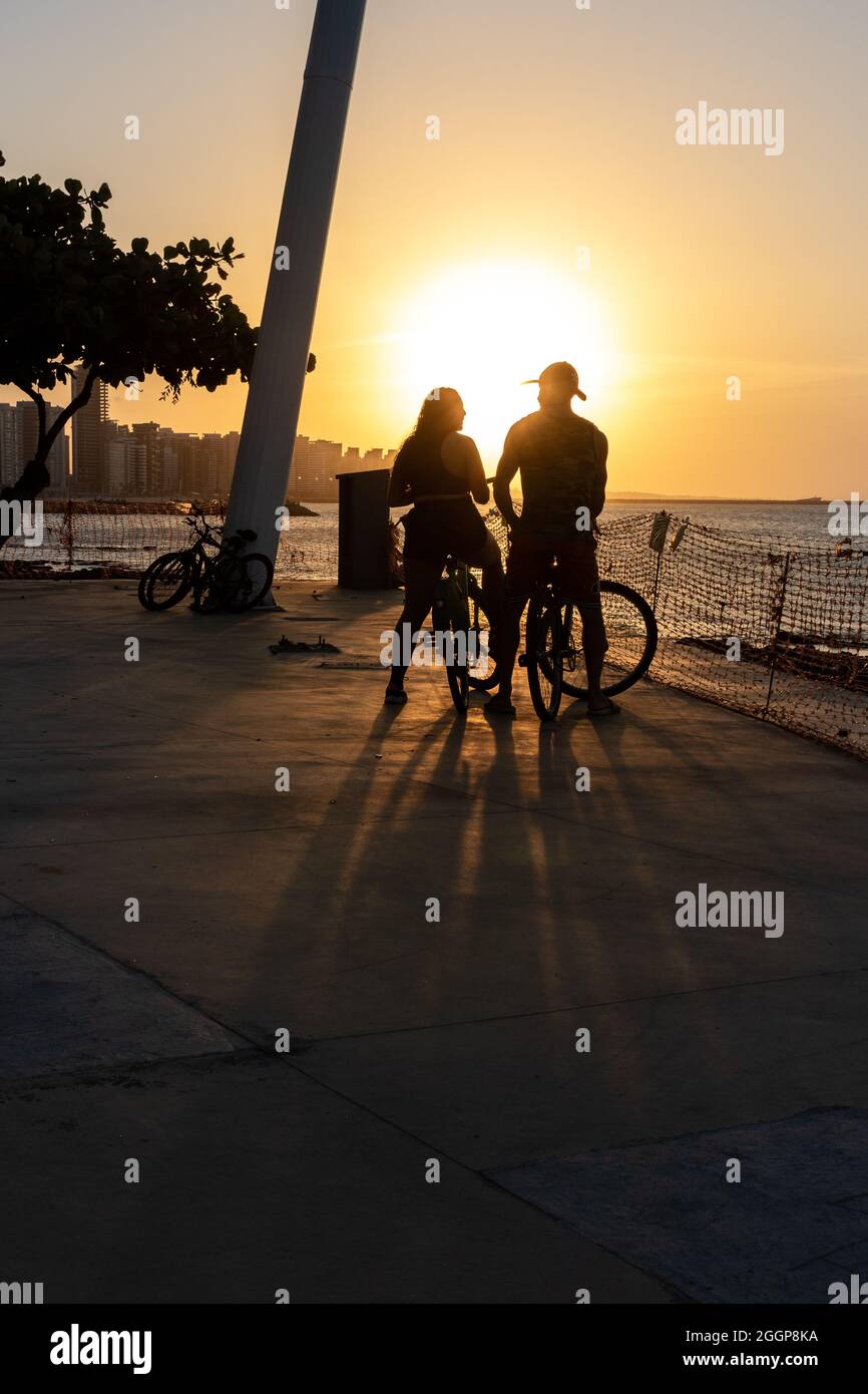 Jeune couple cycliste appréciant le coucher du soleil à Fortaleza Ceara Brésil Banque D'Images