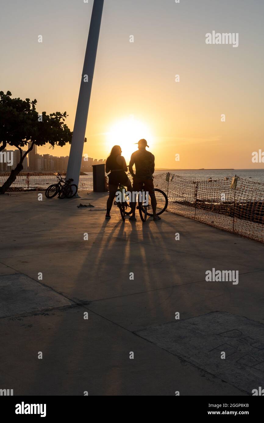 Jeune couple cycliste appréciant le coucher du soleil à Fortaleza Ceara Brésil Banque D'Images