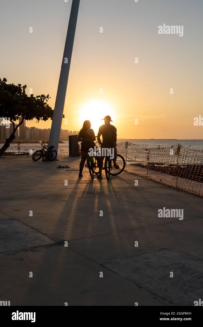 Jeune couple cycliste appréciant le coucher du soleil à Fortaleza Ceara Brésil Banque D'Images