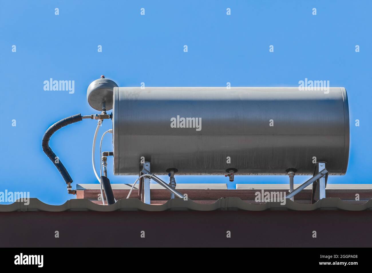 Chauffe-eau système de réservoir et technologie chaude sur le toit de la maison contre le ciel bleu. Banque D'Images