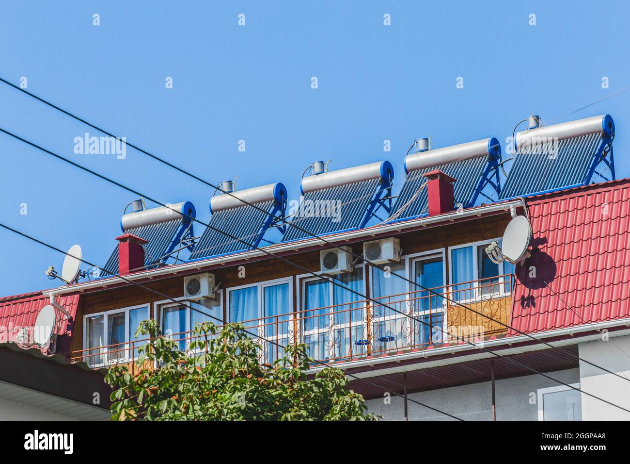 Panneaux solaires thermiques et chauffe-eau technologies alternatives de chauffage de l'eau sur le toit de l'hôtel contre le ciel bleu extérieur. Banque D'Images