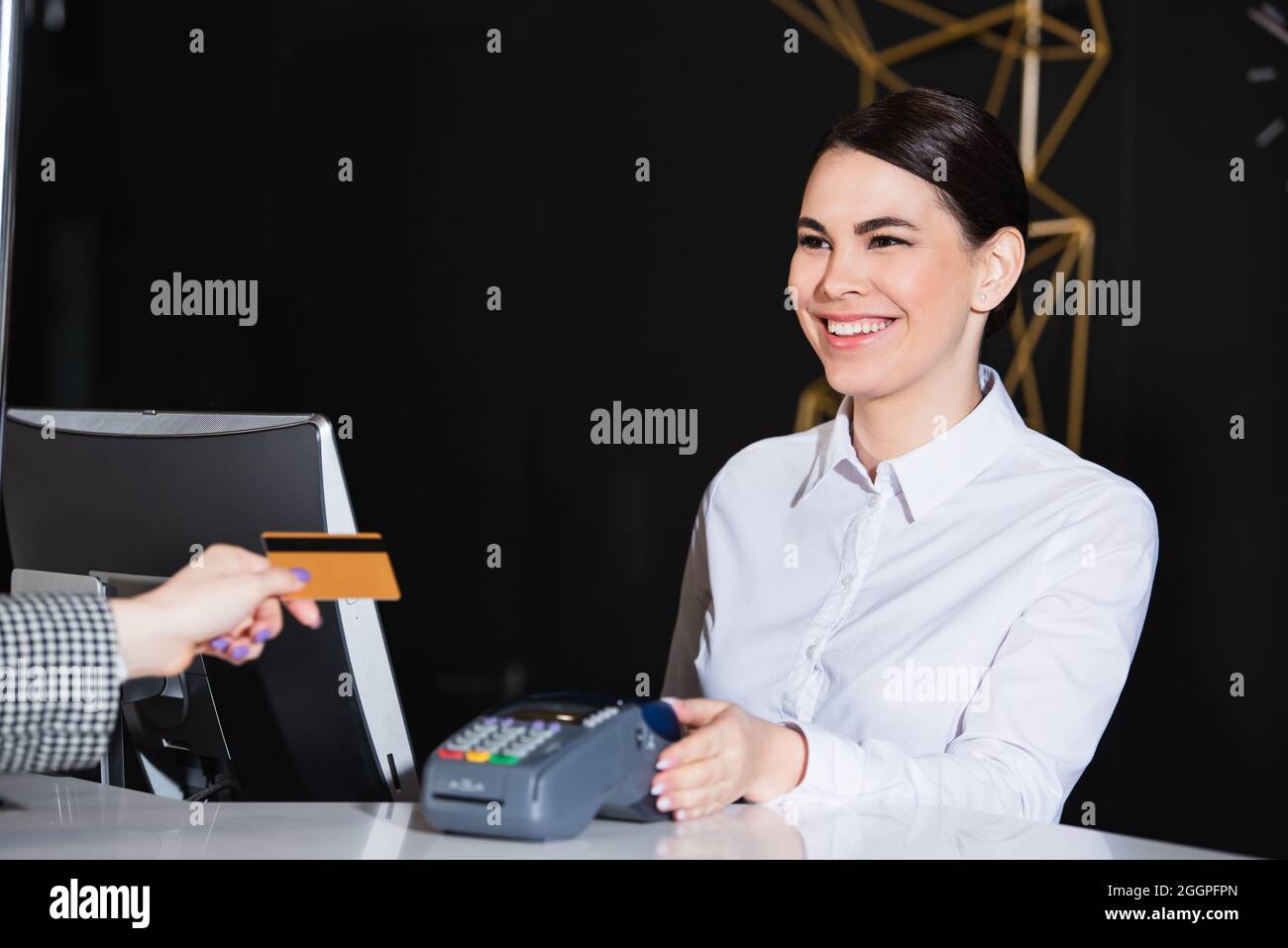 un réceptionniste souriant près d'un client payant avec une carte de crédit Banque D'Images