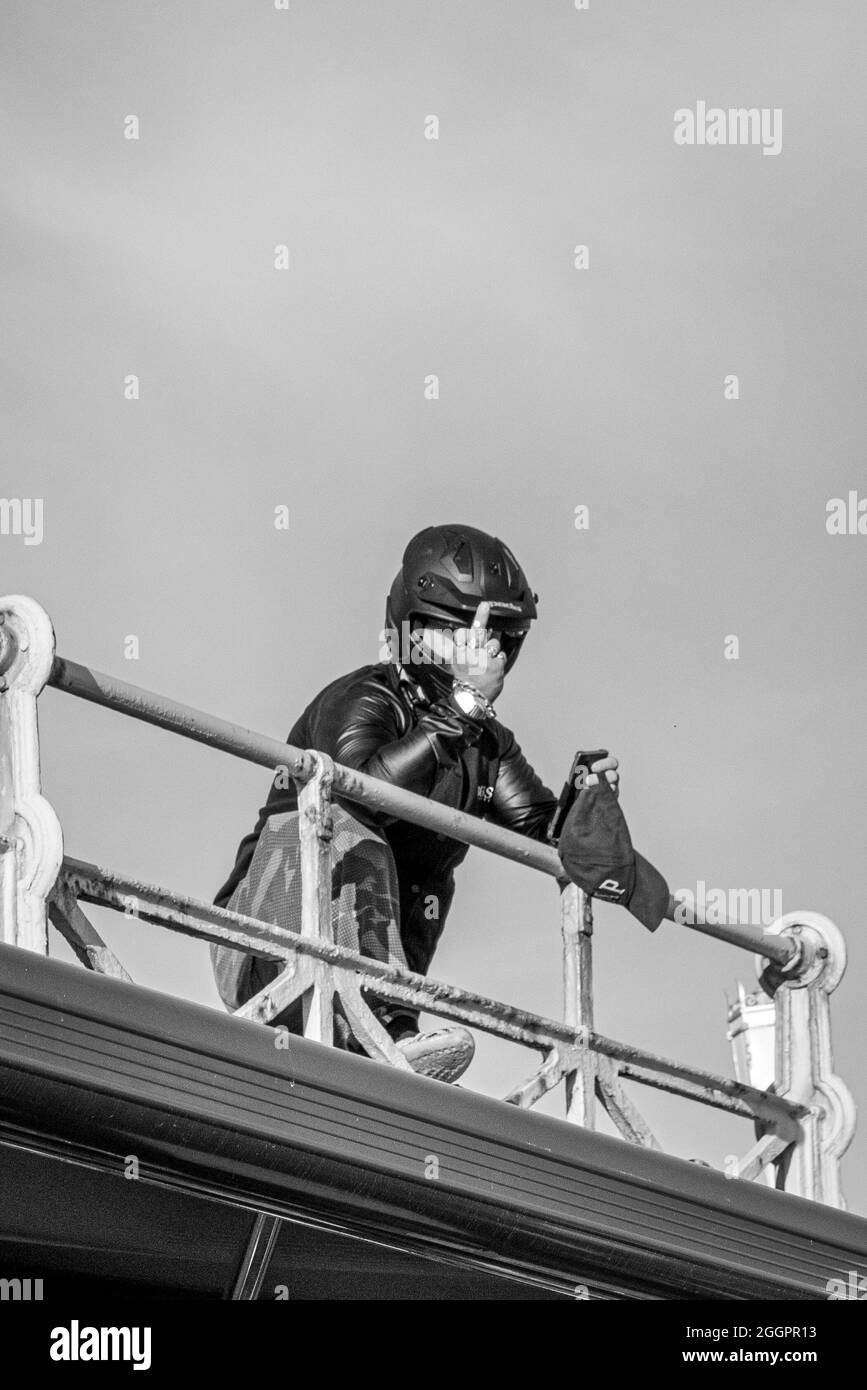 BRIGHTON, ÉMIRATS ARABES UNIS - 16 juin 2021 : photo en niveaux de gris d'une personne qui se penche sur une clôture et montre le doigt du milieu à Brighton, au Royaume-Uni Banque D'Images