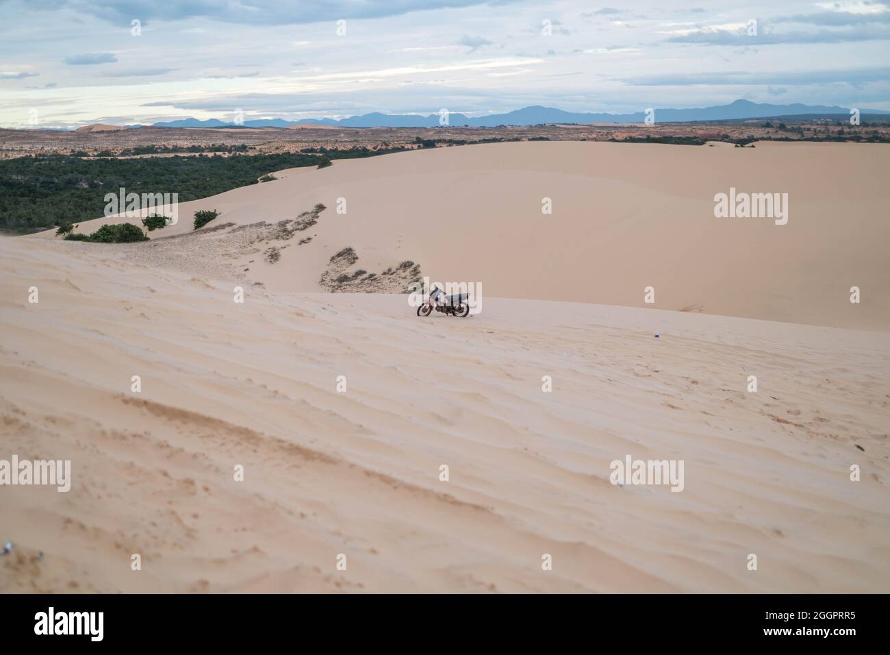 Vue pittoresque de la moto garée sur les dunes de sable dans le désert. Journée ensoleillée pendant les vacances d'été. Dunes de sable. Moto dans le désert. Banque D'Images