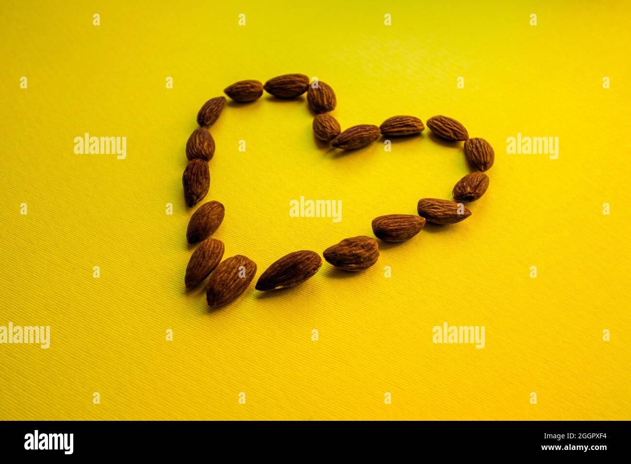 Les amandes sont disposées sur un fond jaune en forme de coeur. Banque D'Images