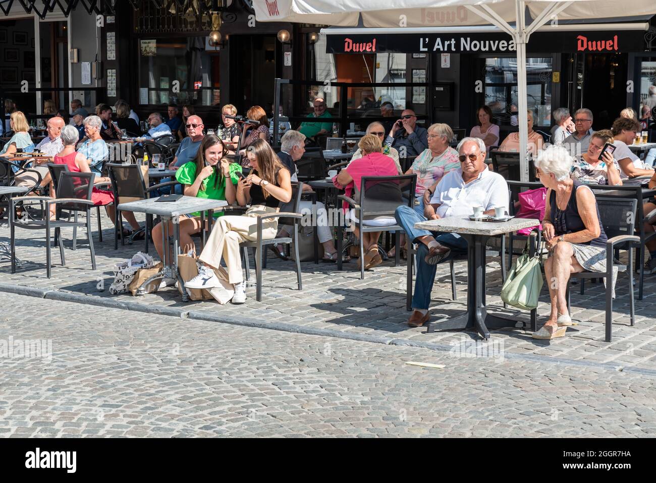 Personnes assises sur une terrasse ensoleillée en été sur la place principale du marché Banque D'Images