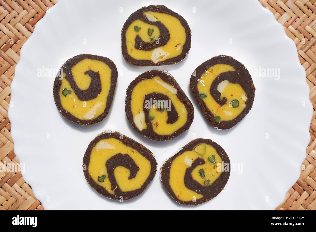 Sucré indien appelé « rouleau de barfi au chocolat ». Burfi est un plat sucré à base de lait. Spirale conçue avec goût Kesar pista chocolat et lait. Arrière-plan Banque D'Images