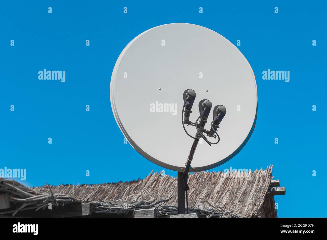 Antenne parabolique et technologie de signal tv sur le toit de la maison sur fond de ciel bleu. Banque D'Images