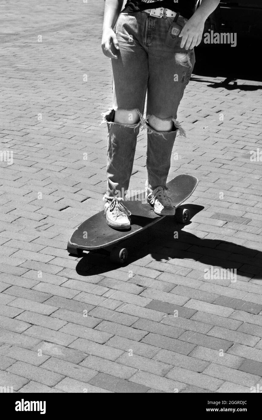Une adolescente fait un skateboard le long d'une route en briques à Santa Fe, au Nouveau-Mexique. Banque D'Images
