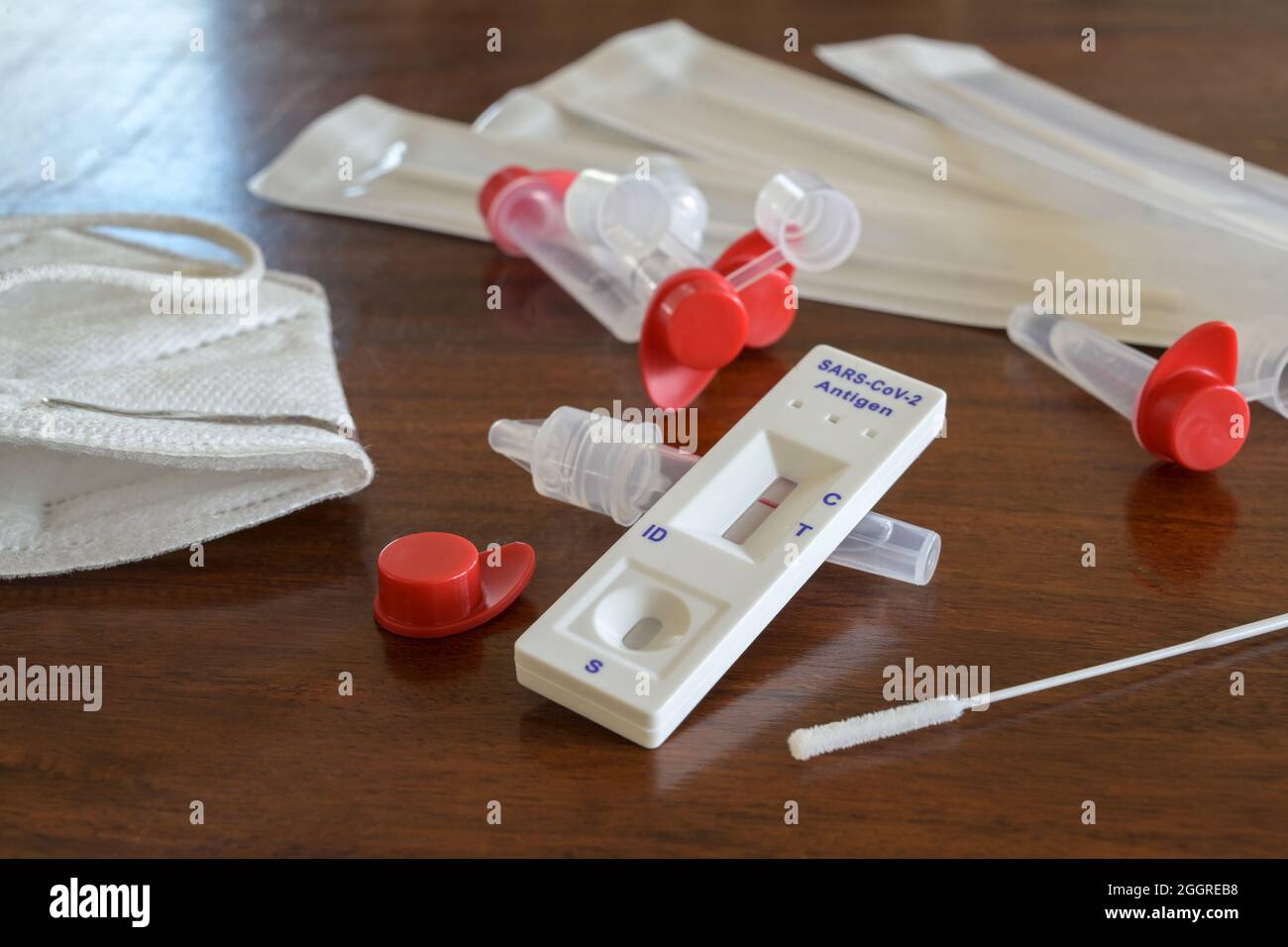 Test automatique d'antigène Covid-19 rapide avec résultat négatif, écouvillons nasaux, tubes et dispositif de détection sur une table en bois, utilisé pour le diagnostic de masse à la maison, à Banque D'Images