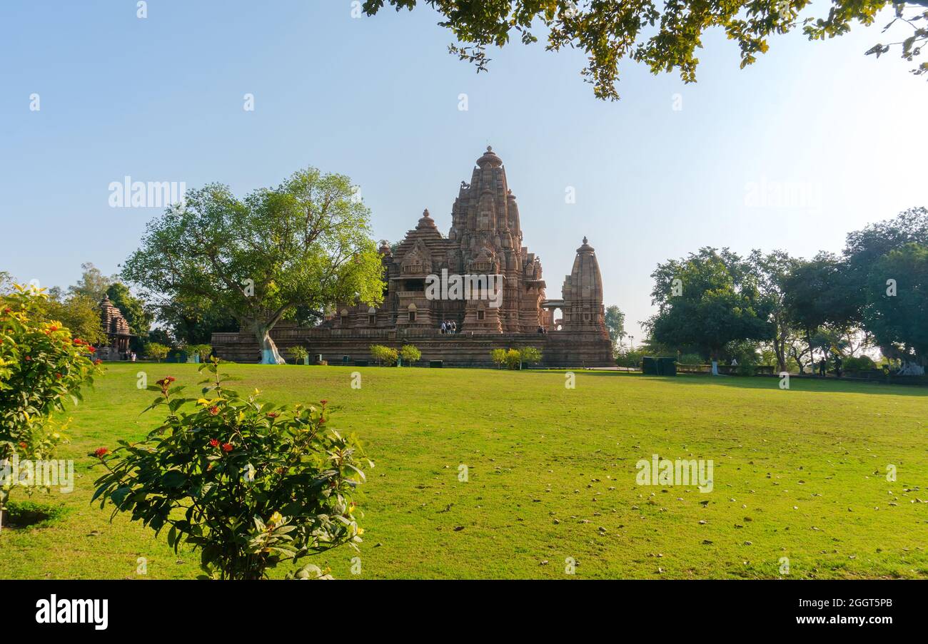 Ancien et plus jeune temple hindou, construit par Chandela Rajputs, sur le site occidental de Khajuraho en Inde encadré par des arbres. Gris blanc pour les plus jeunes et les plus âgés Banque D'Images