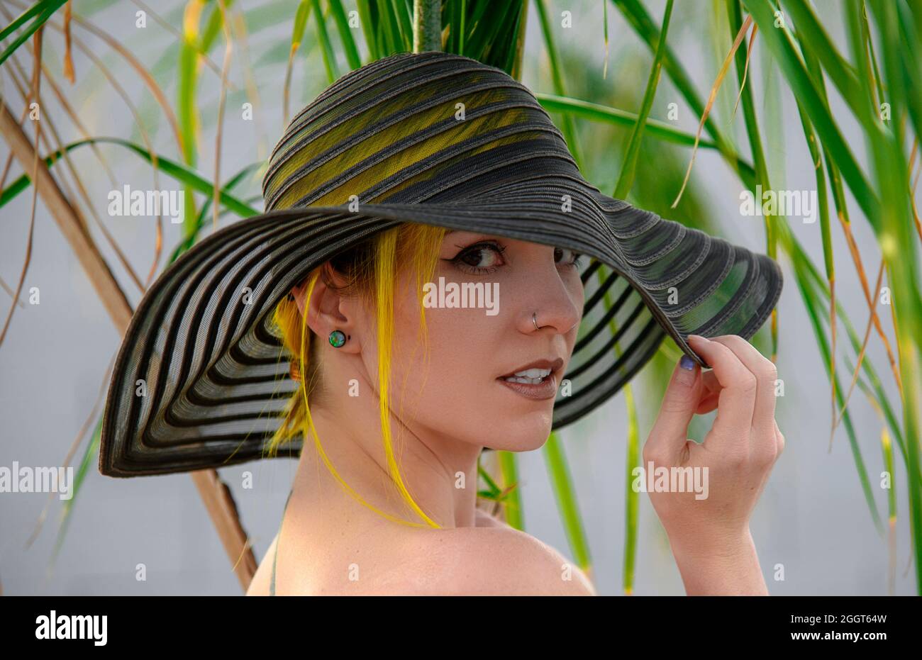 Belle jeune femme portant un chapeau de soleil sous un palmier Banque D'Images
