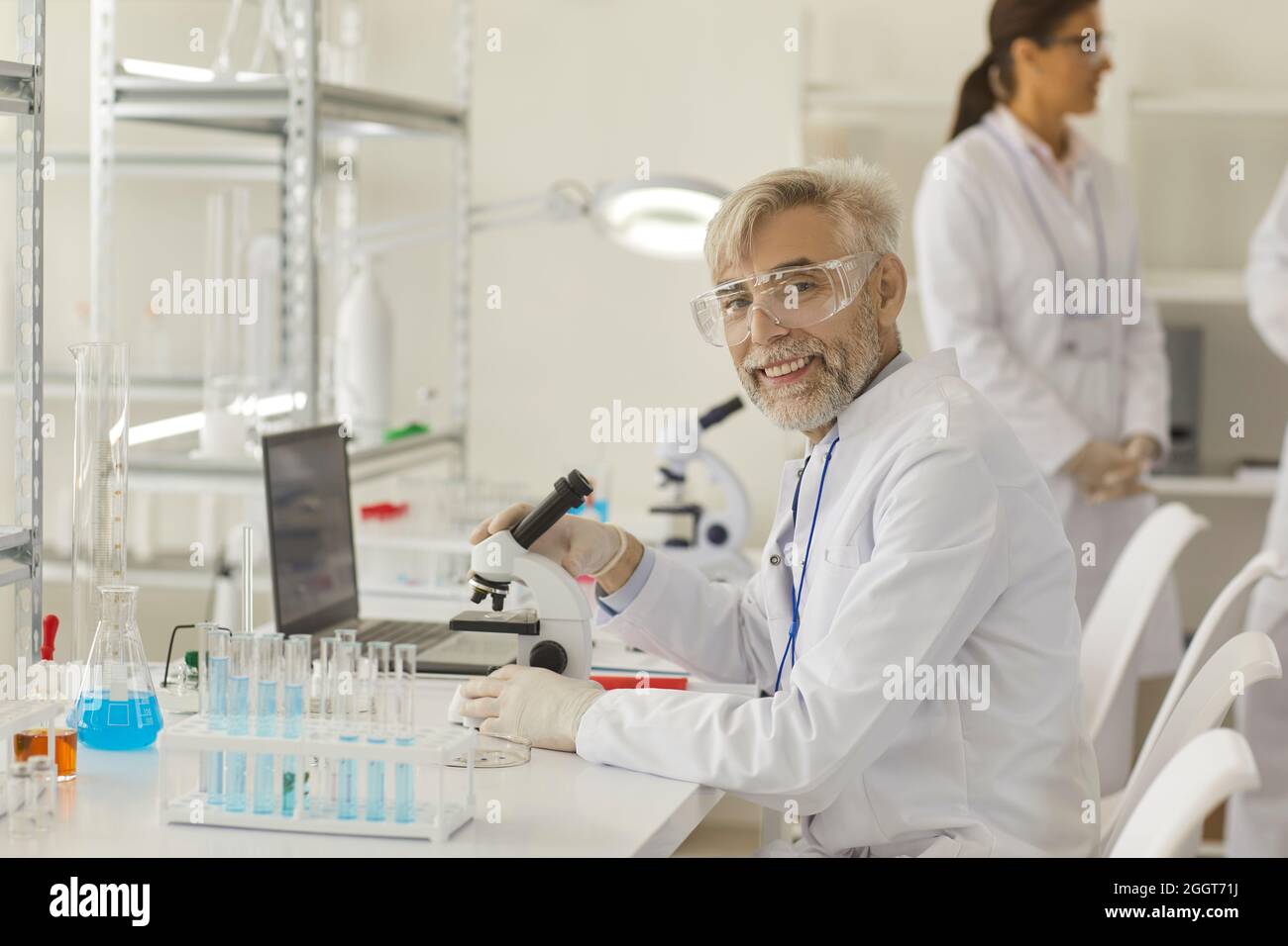 Portrait d'un scientifique expérimenté travaillant avec un microscope, un ordinateur portable et un équipement de laboratoire Banque D'Images