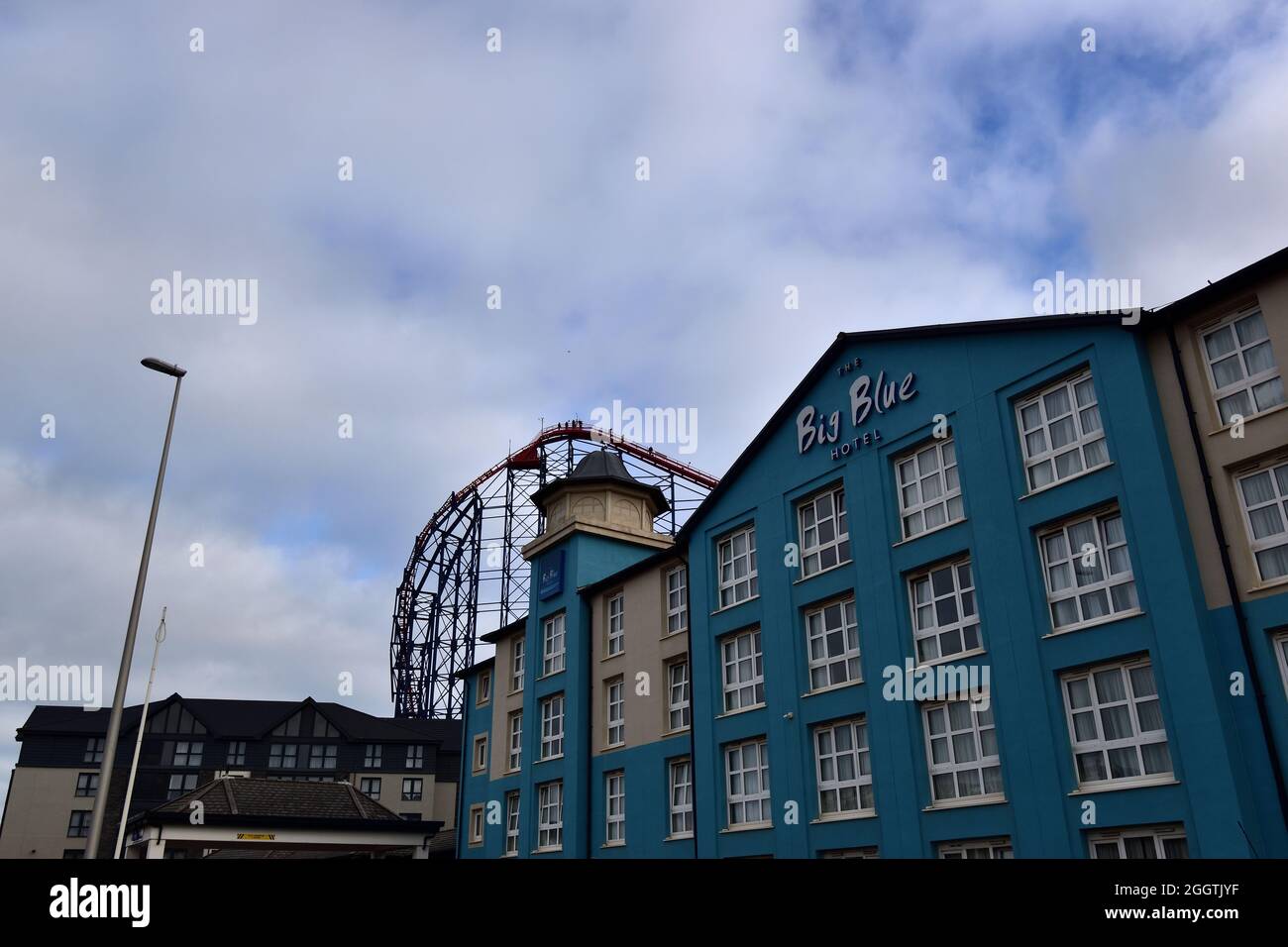 L'hôtel Big Blue, Blackpool, Royaume-Uni, avec des personnes grimpant les montagnes russes Big One en arrière-plan Banque D'Images
