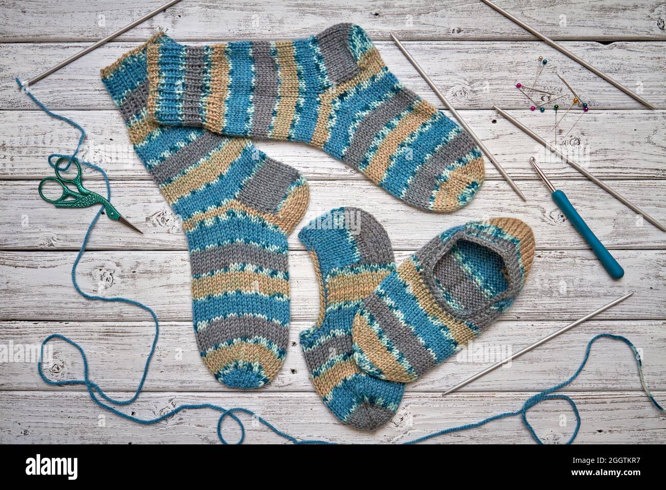 Deux chaussettes et pantoufles tricotées pour enfants sur fond de bois clair Banque D'Images