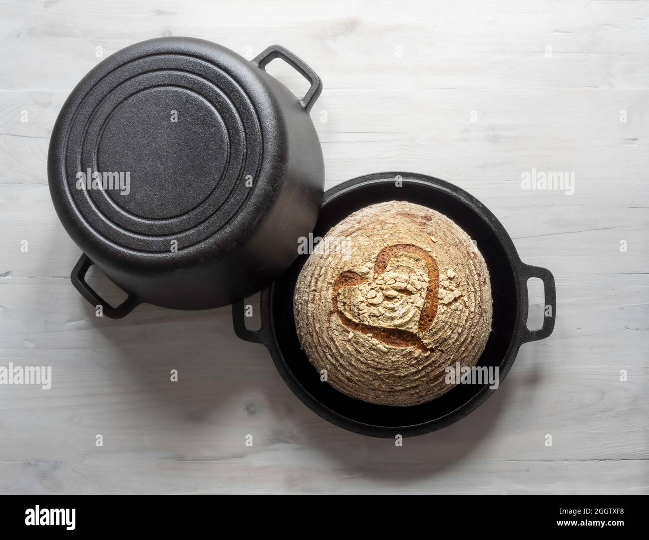 Pain de levain sans gluten cuit dans une casserole hollandaise en fonte avec motif coeur marqué dans la surface de la croûte. Banque D'Images