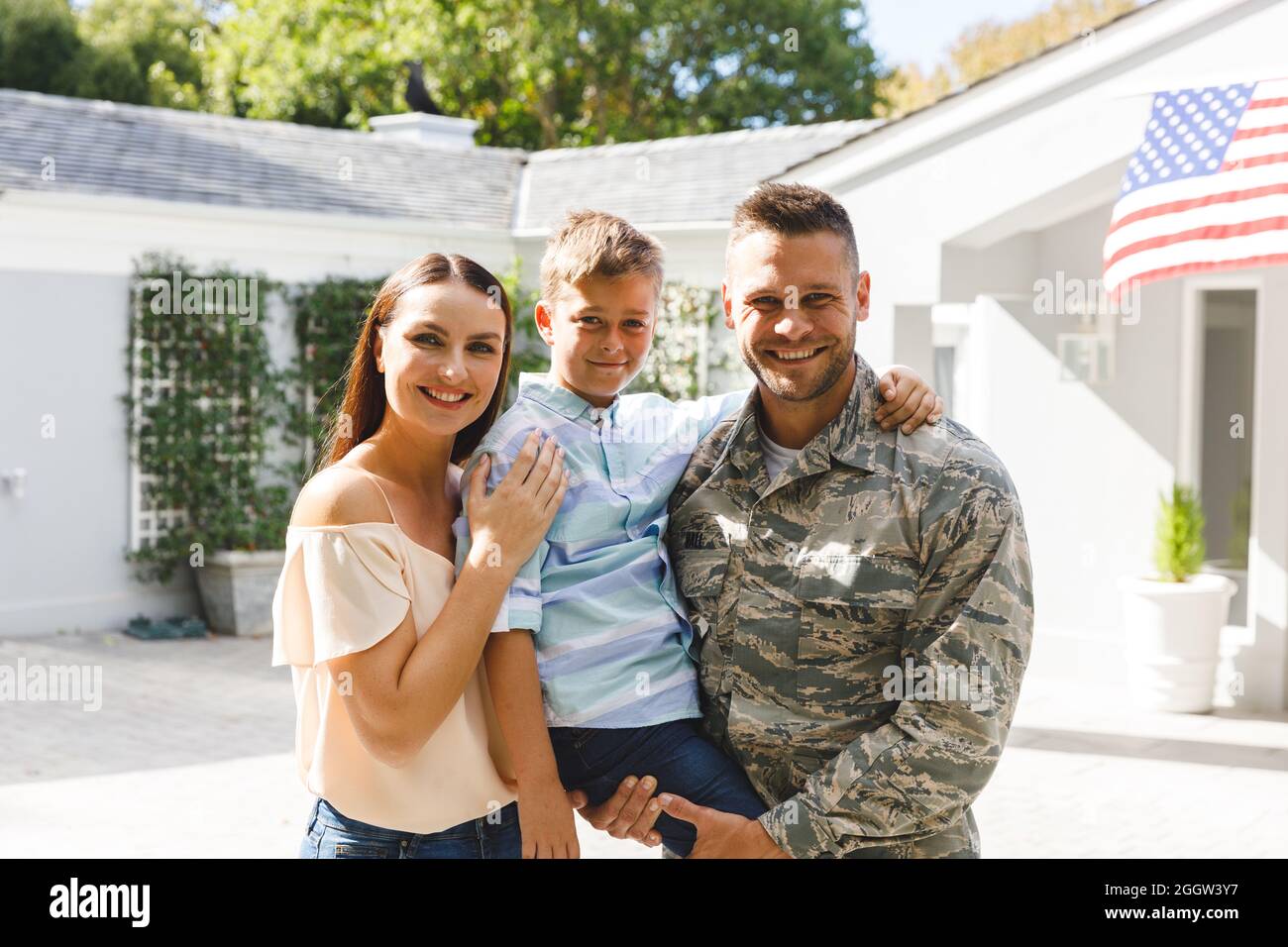 Portrait d'un soldat de race blanche avec son fils et sa femme à l'extérieur de la maison décoré d'un drapeau américain Banque D'Images