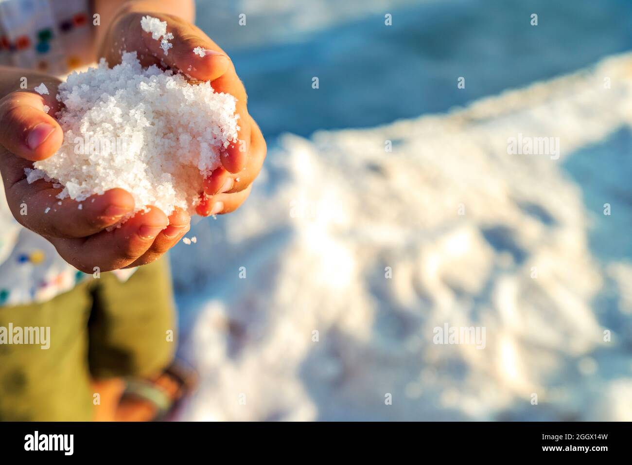 Un petit garçon tenant un cristal de sel frais dans ses mains à salines à Faro, Algarve, Portugal Banque D'Images