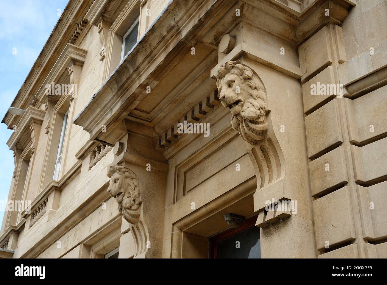 Une grande entrée à un bâtiment en pierre. Têtes de lions de grès sculptées. Banque D'Images