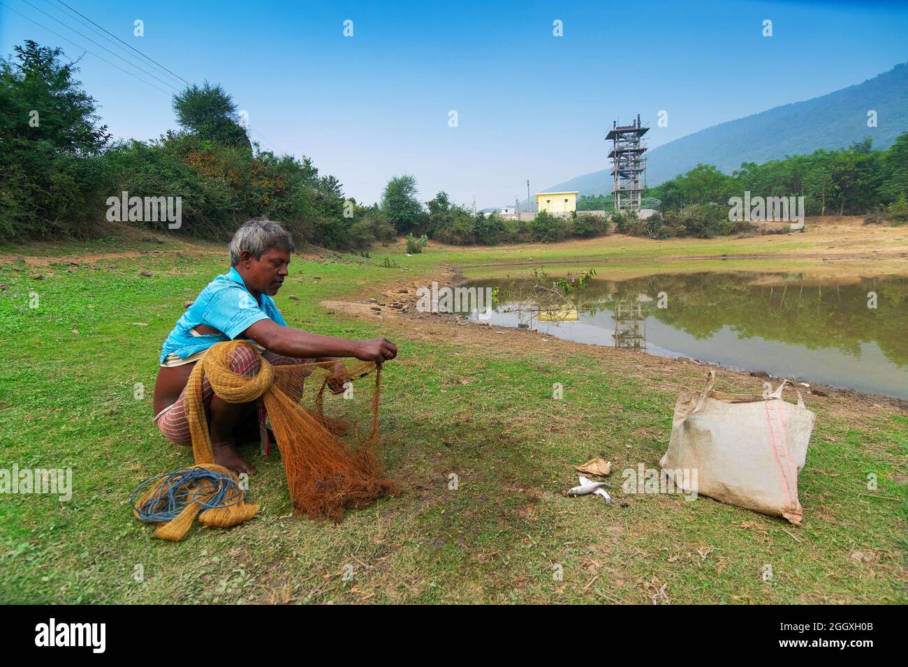 Gar Panchkot, Purulia , Bengale-Occidental, Inde - 23rd décembre 2015 : Un pêcheur solitaire comptant les poissons capturés de l'étang. Inde ayant de nombreux étangs . Banque D'Images