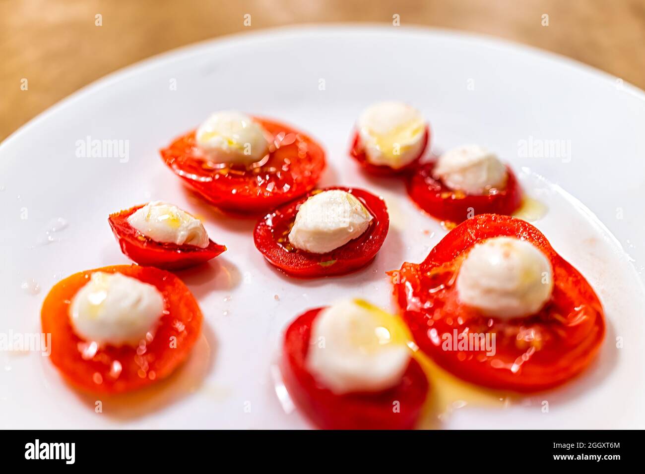 Gros plan sur une assiette blanche avec de petites tomates fraîches en tranches, du fromage mozzarella arrosé d'huile d'olive sous forme d'en-cas ou d'apéritif sous forme de câpres alimentaires d'inspiration italienne Banque D'Images Gros plan sur une assiette blanche avec de petites tomates fraîches en tranches, du fromage mozzarella arrosé d'huile d'olive sous forme d'en-cas ou d'apéritif sous forme de câpres alimentaires d'inspiration italienne Banque D'Images