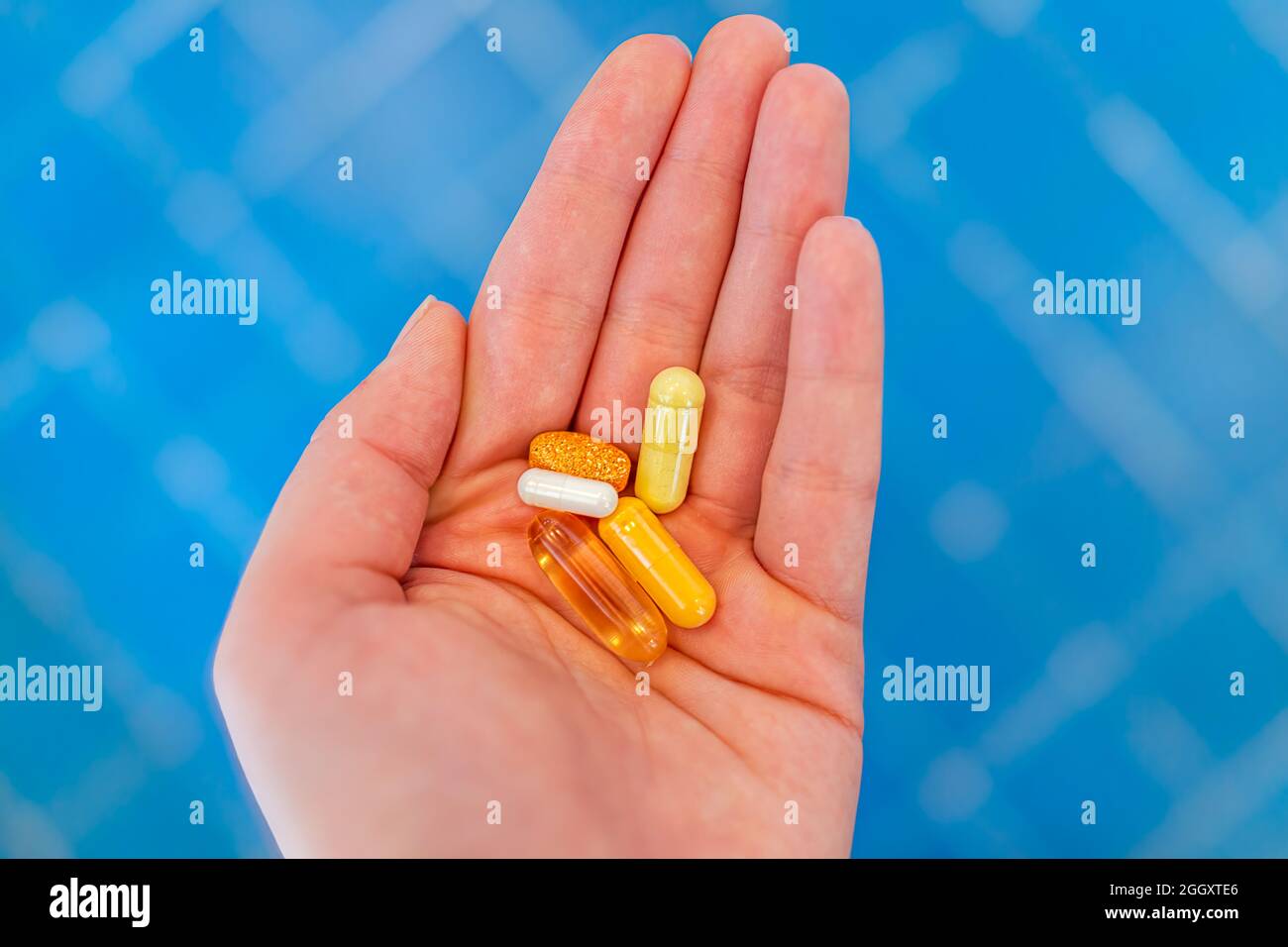Gros plan de la jeune femme main tenant des pilules de médicament de supplément dans la paume comme la vitamine c et b et l'huile de poisson Banque D'Images